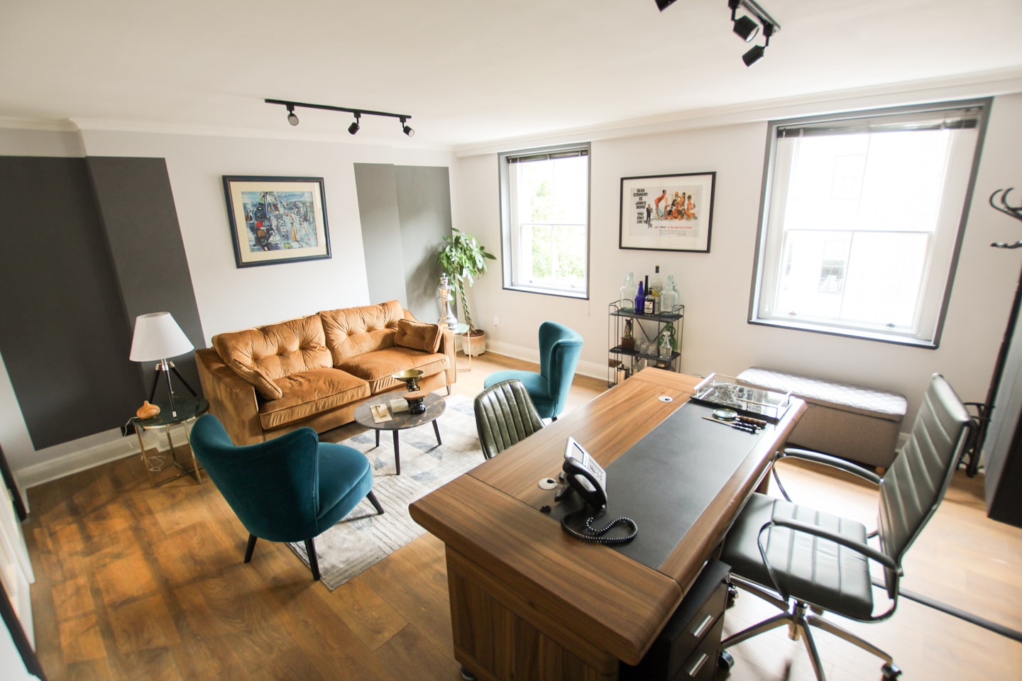 Contemporary office space with sofa, armchairs, and desk.